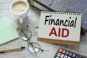 desk table with mug of coffee, glasses, calculator, notebook with financial aid written out