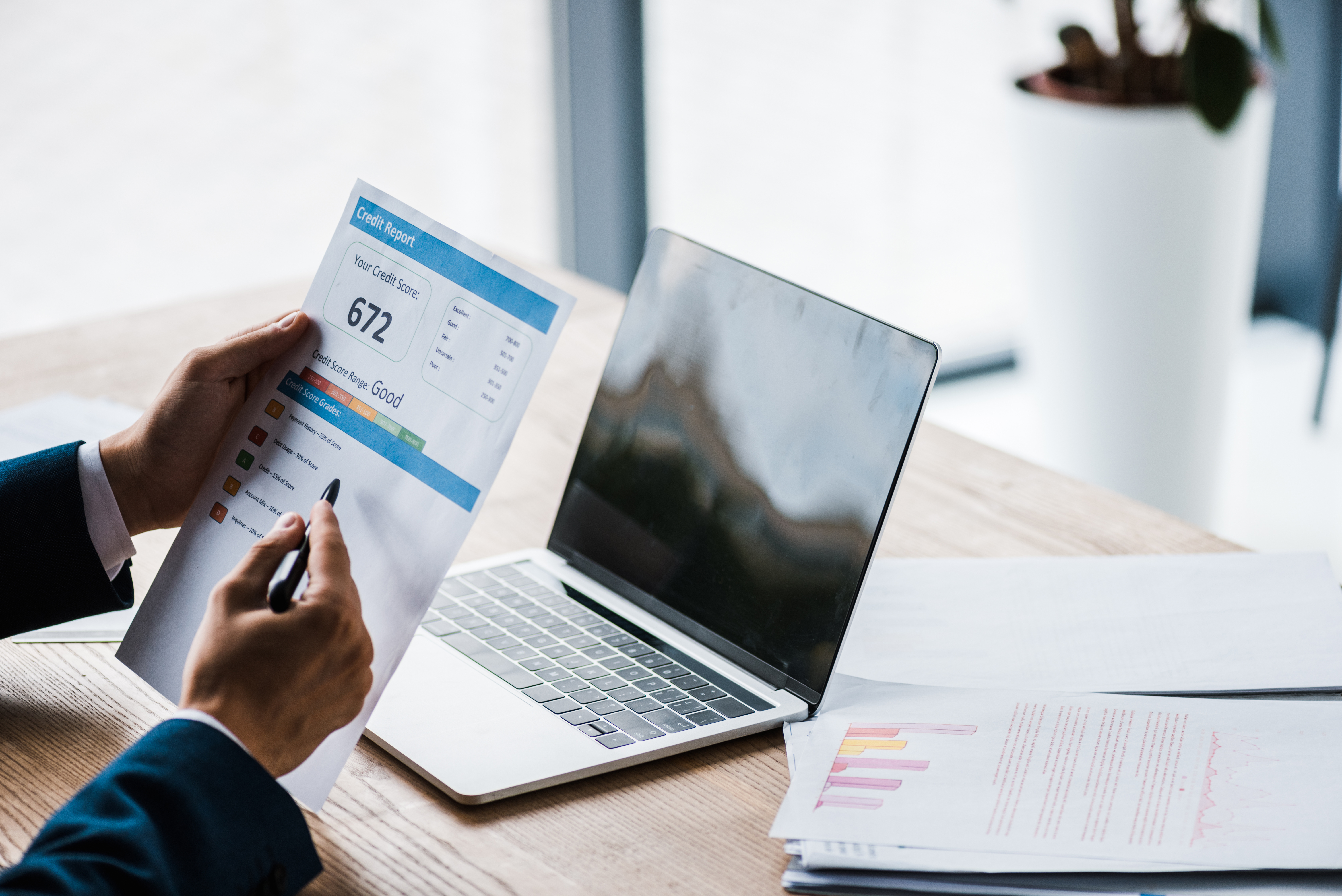 hands holding credit report sitting at desk