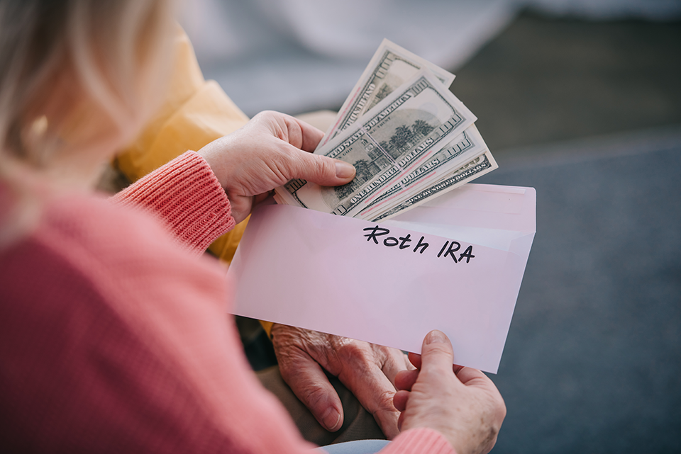 Woman holding white envelope pulling out small stack of money.