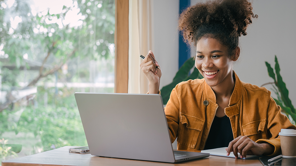 Young smiling woman working on laptop and notepad