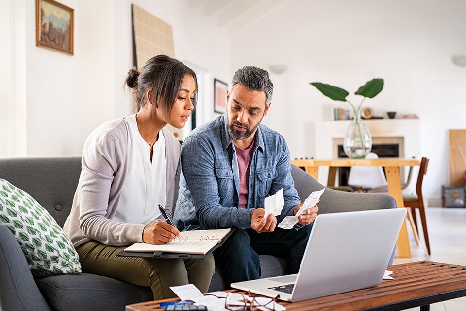 Woman and man sitting on couch working on home finances