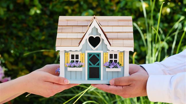 Hands holding a toy replica of a house