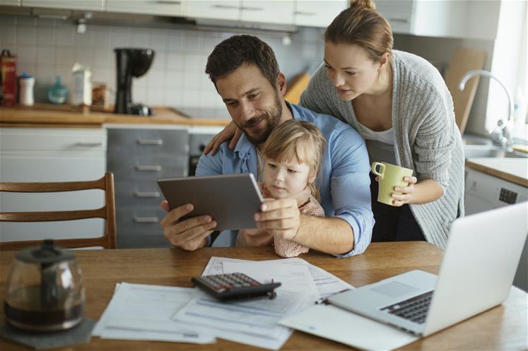 Family using tablet and computer in kitchen