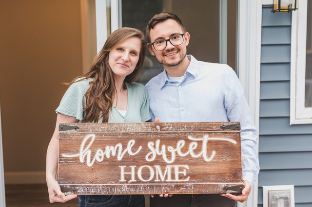 Young couple holding wooden home sweet home sign
