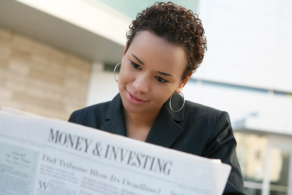 woman reading money and investing newspaper