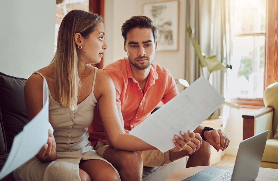 Stressed man and woman sitting on couch going over finances.