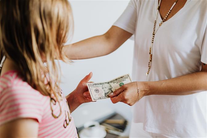 Parent handing child ten dollars