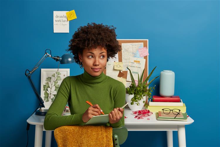 Woman sitting in front of desk writing in notebook