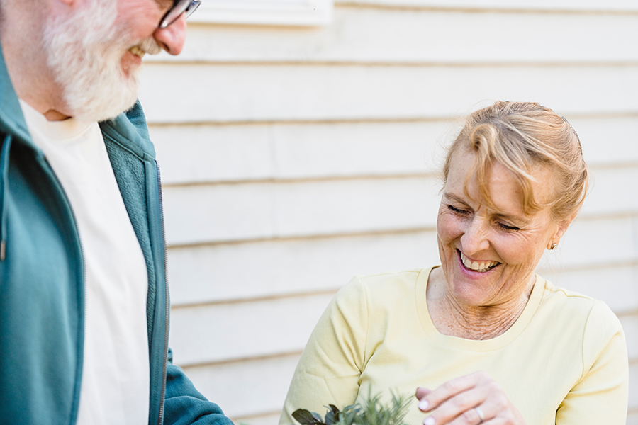 Smiling senior man and woman holding plant