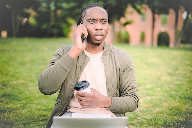 Concerned man sitting in park on mobile phone.