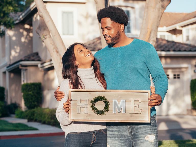 Couple holding home sign