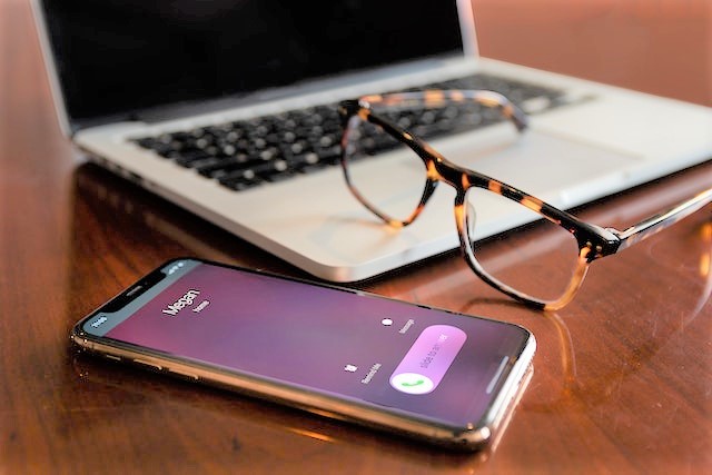 Mobile phone, laptop and glasses on wooden table