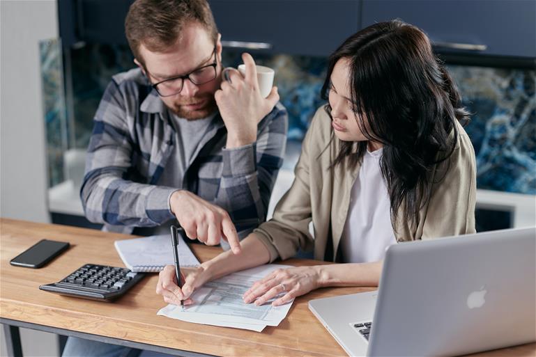 Man and woman sitting down discussing budget over paperwork