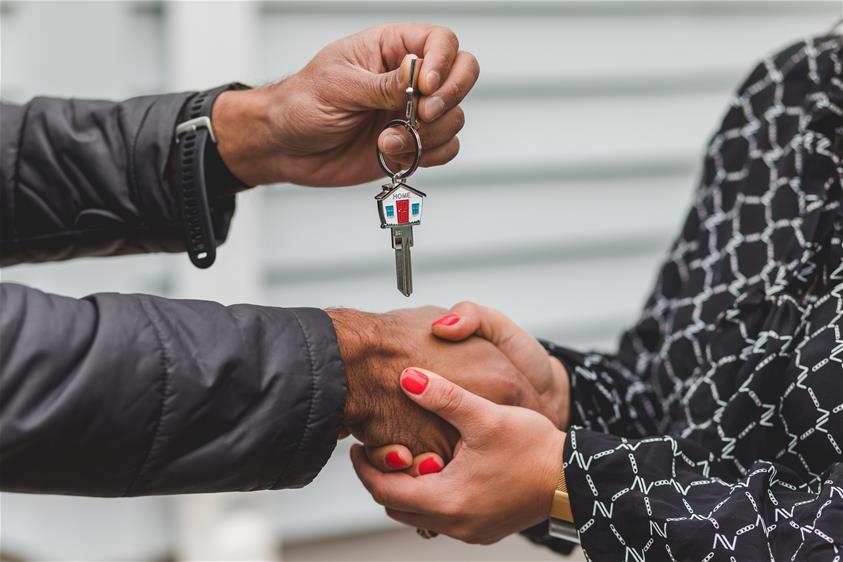 two individuals shaking hands while exchanging house keys
