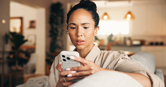 Worry, woman and reading with phone while sitting on couch