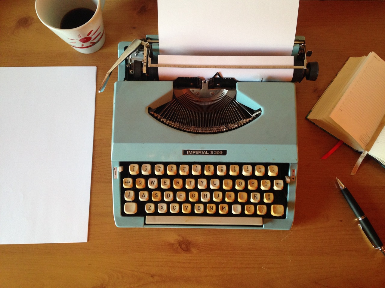 green typewriter on wooden desk.