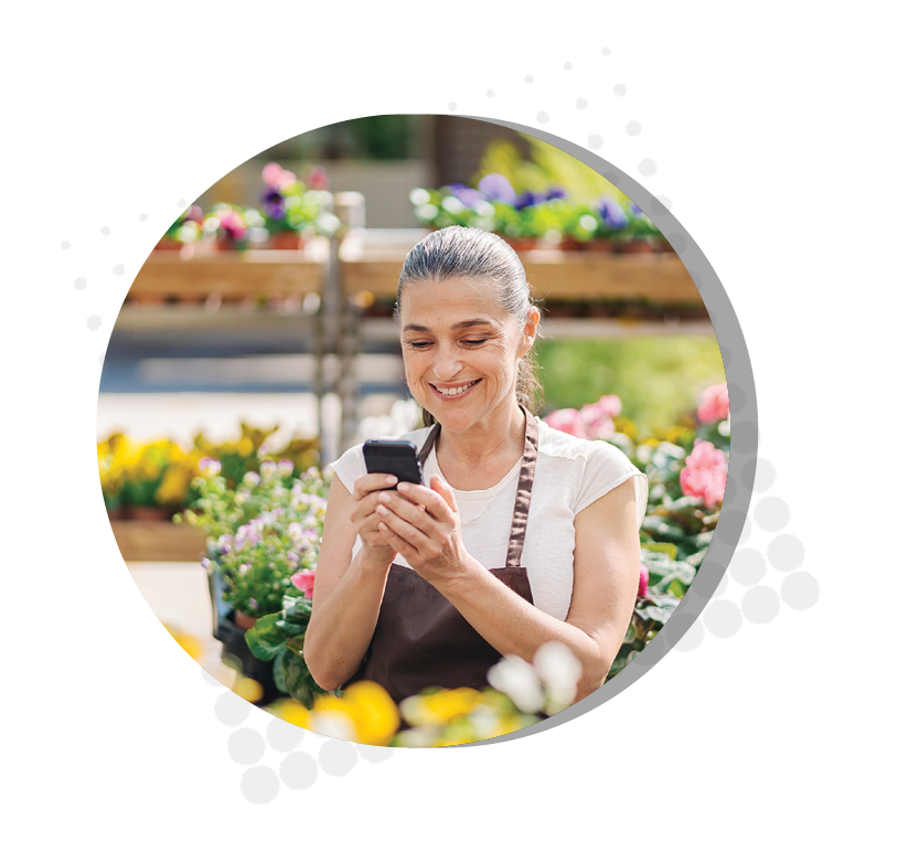 florist sitting in garden smiling down at phone