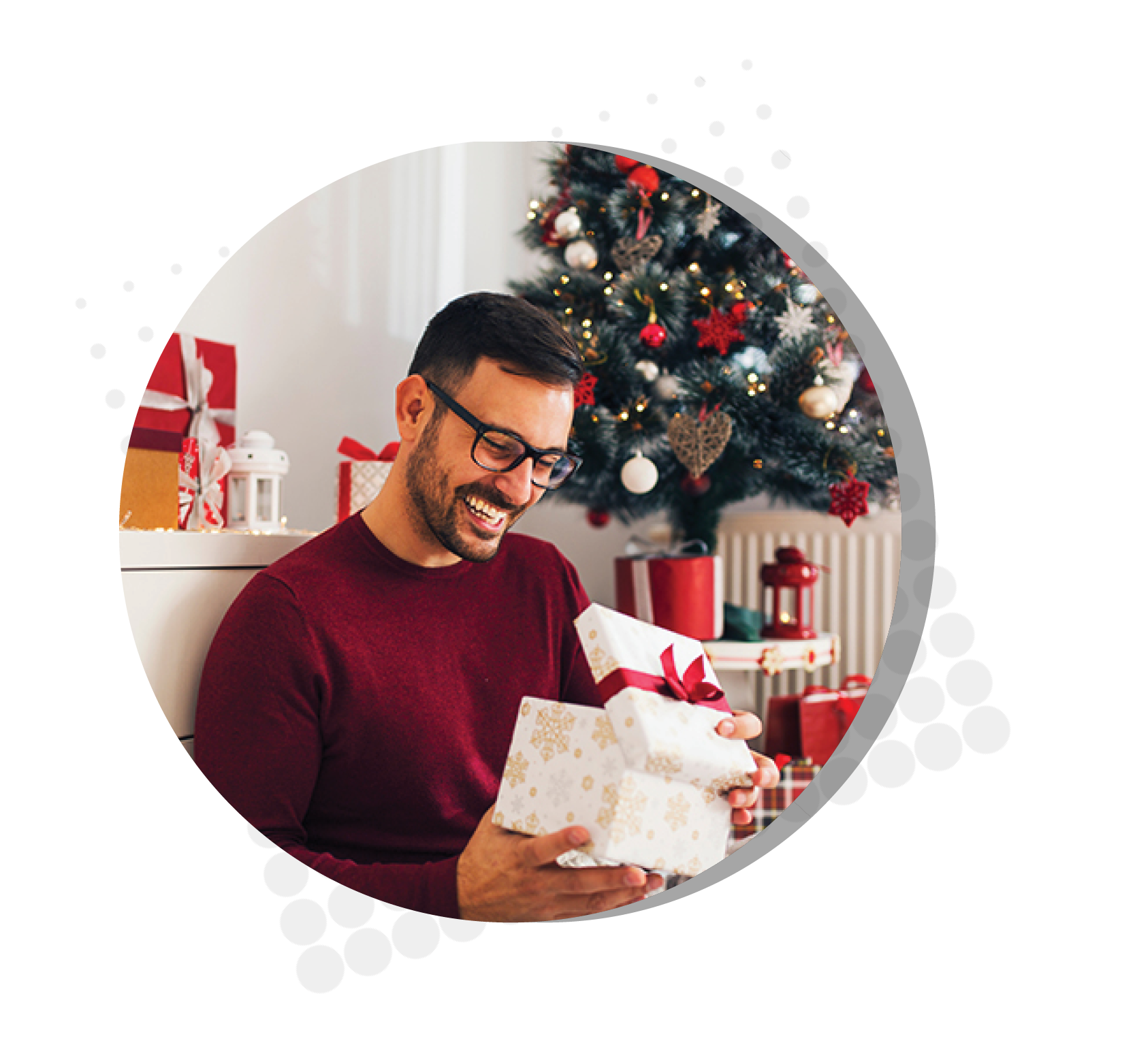 man smiling opening present sitting next to Christmas tree