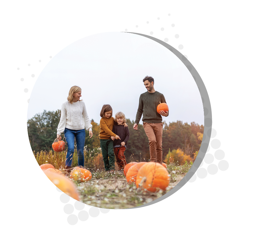 mother and father walking through pumpkin patch smiling at kids walking between them