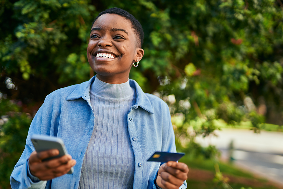 Woman Smiling holding credit card and mobile phone