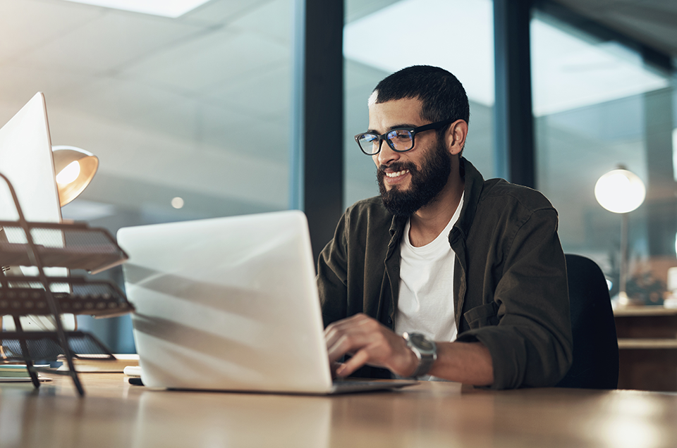 Smiling man while typing on laptop