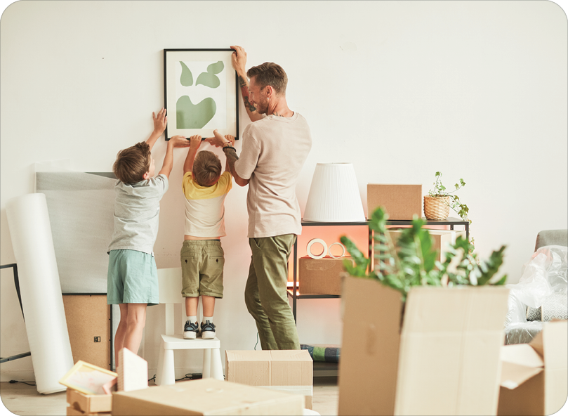 father, sons hanging picture in home