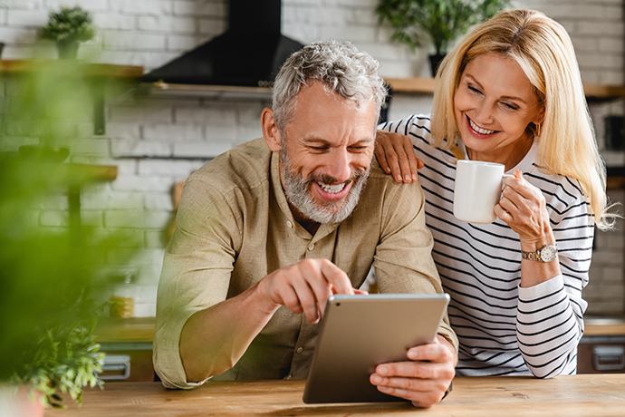 Happy couple using digital tablet in kitchen at home