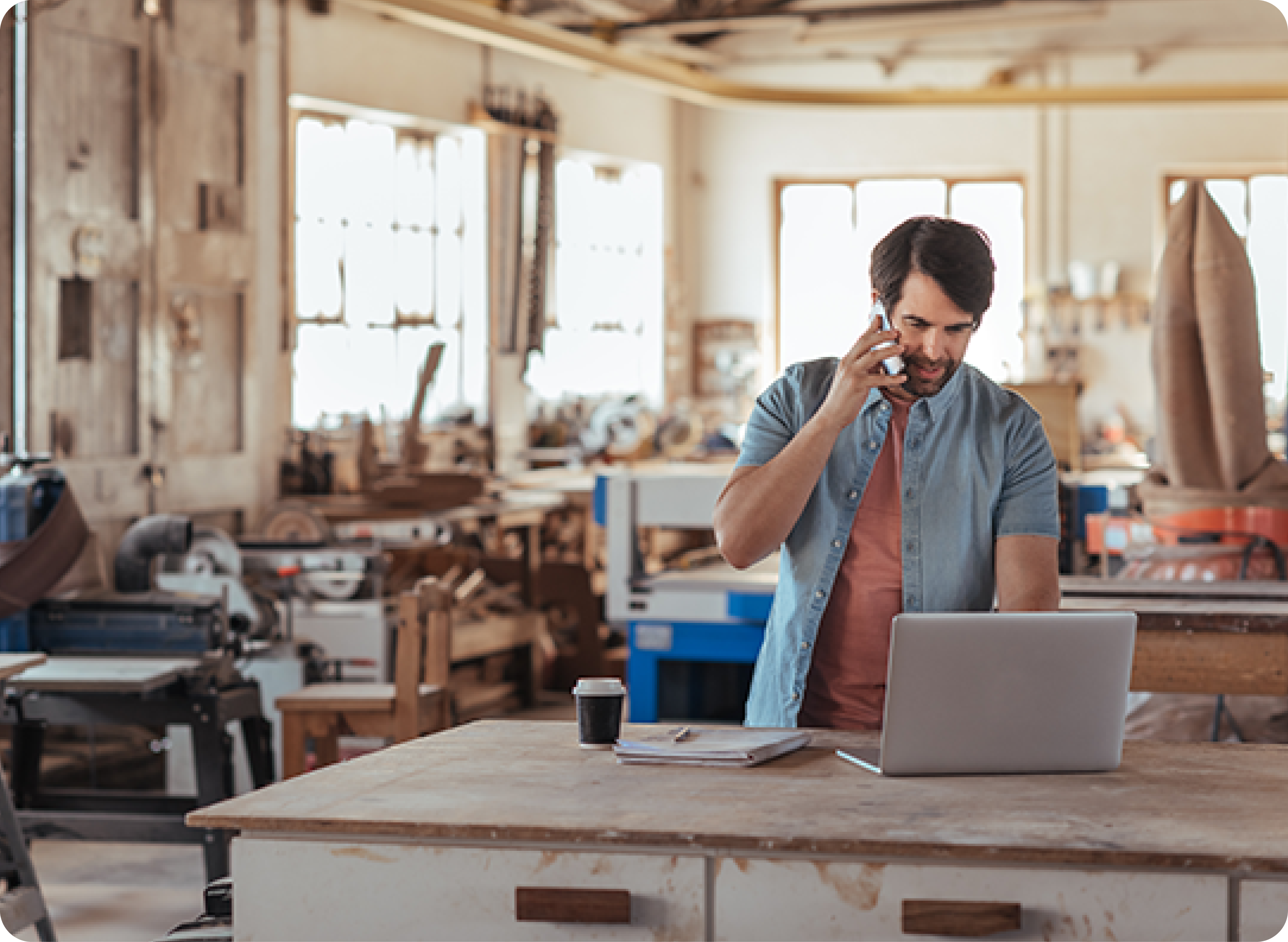 Man working in workshop talking on phone Man working in workshop talking on phone