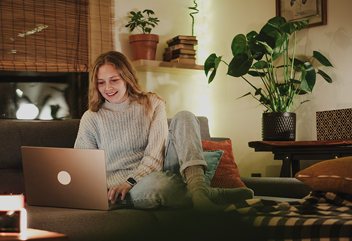 woman sitting on cozy couch working on laptop