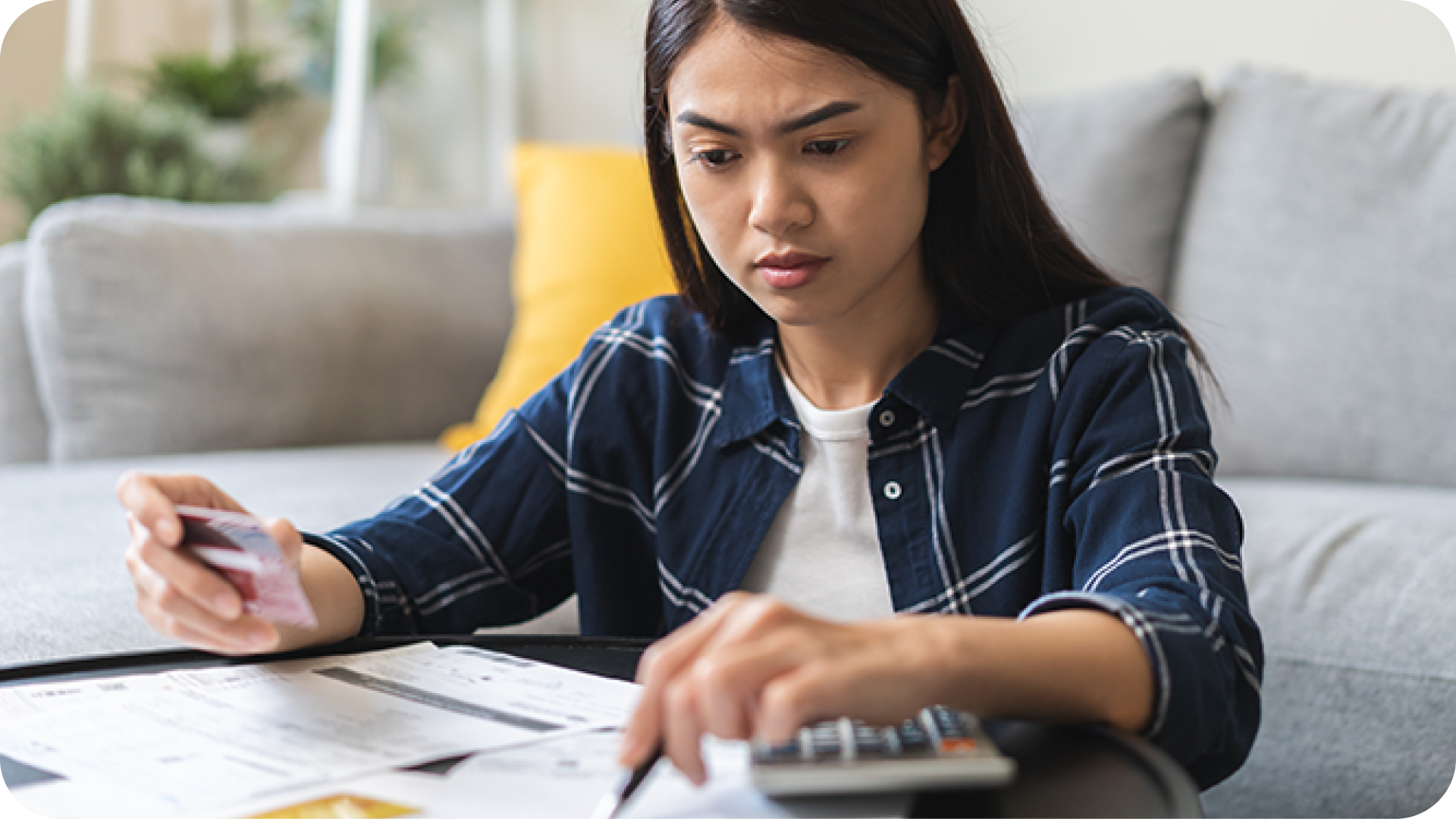 woman sitting on living room floor looking pensively at credit card bills
