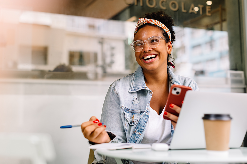 Young woman college student sitting in coffee shop using smartphone