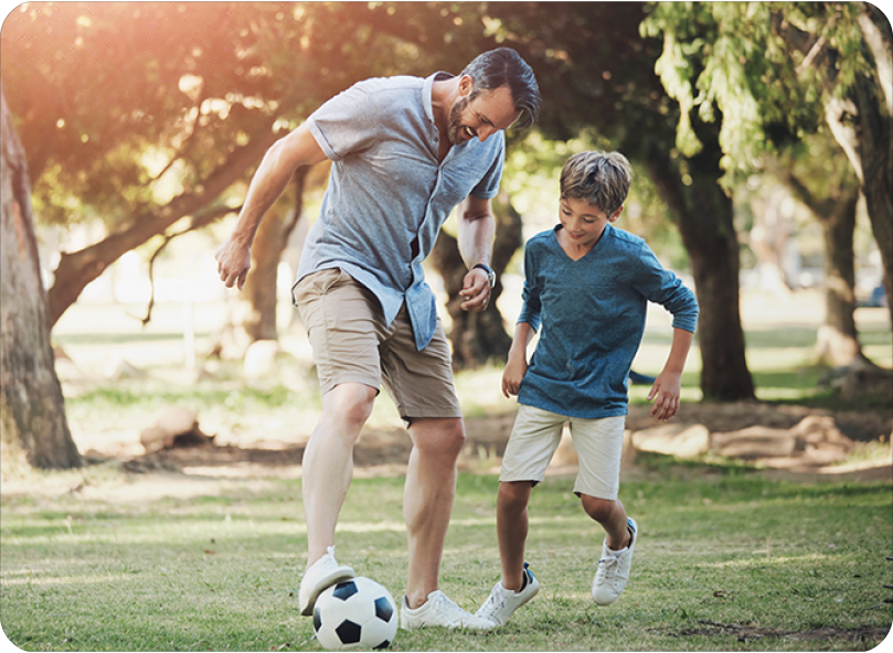 father and son in park playing soccer