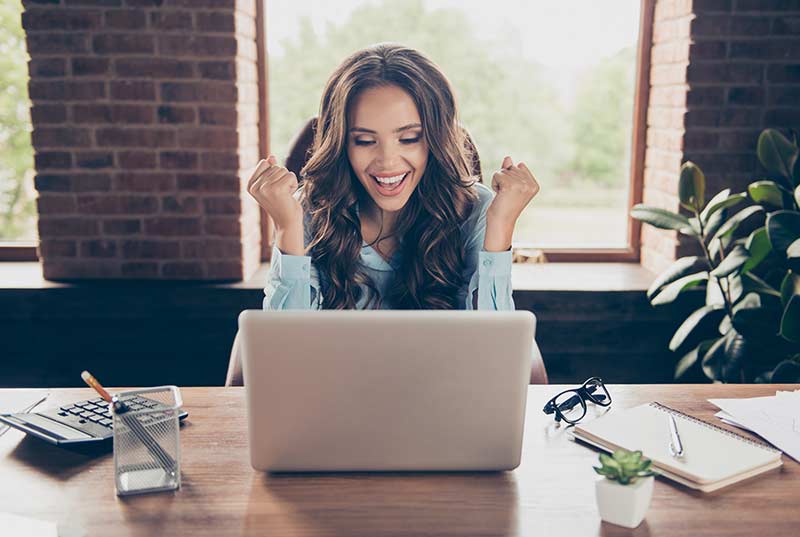 woman celebrating in front of laptop
