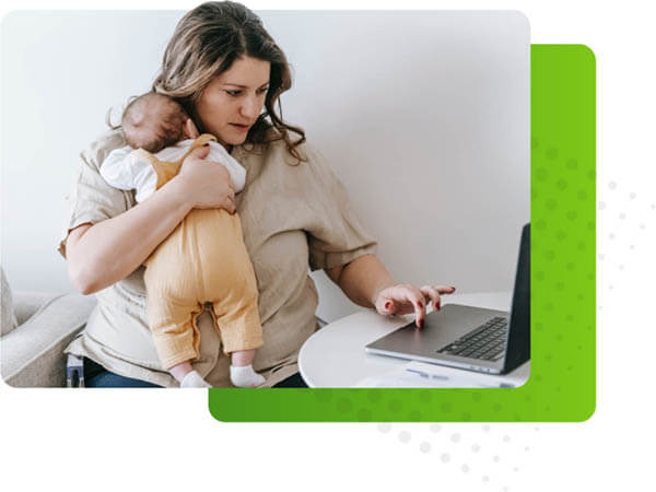 Woman holding infant and using laptop