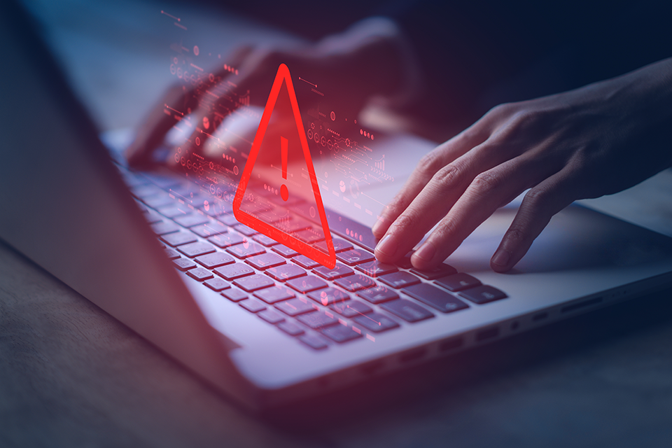 Phishing Scam hands on a keyboard with alert icon on top