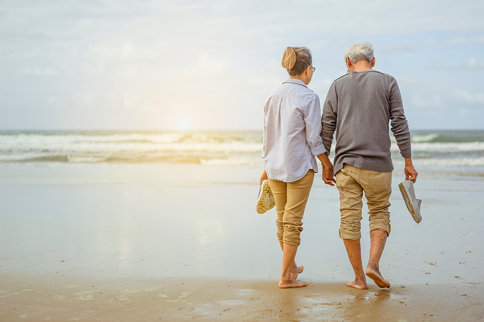 Happy senior couple holding hands walking on the beach. Happy senior couple holding hands walking on the beach.