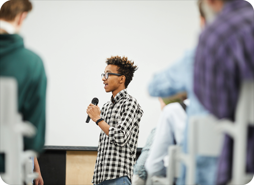confident student standing in classroom presenting on microphone confident student standing in classroom presenting on microphone