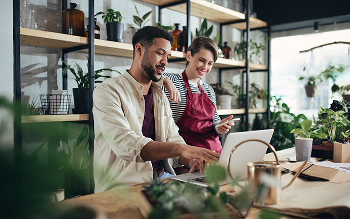 Shop assistants with laptop working in potted plant store Shop assistants with laptop working in potted plant store