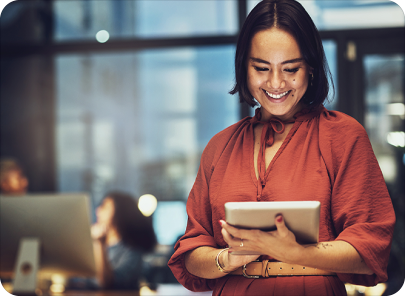 Corporate woman in office smiling down at tablet Corporate woman in office smiling down at tablet