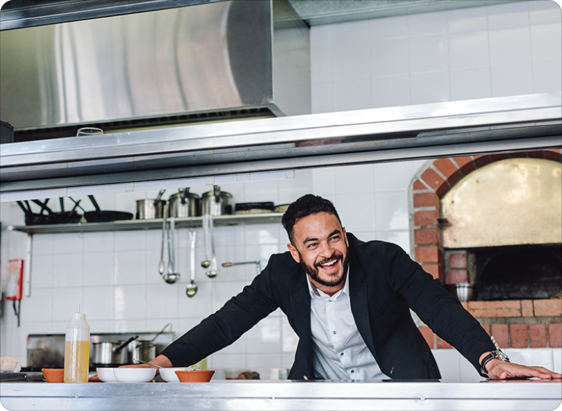 Smiling restaurant owner standing at kitchen counter Smiling restaurant owner standing at kitchen counter